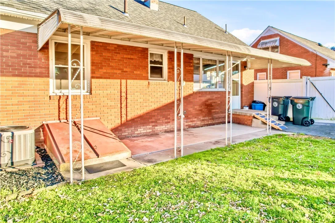 View of home's exterior with roof with shingles, brick siding, a patio, and a chimney