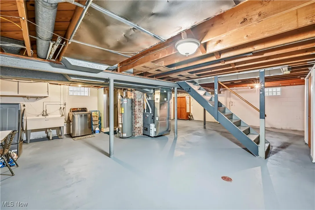 Basement featuring stairway, heating unit, water heater, and washer and clothes dryer