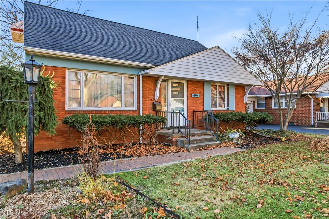 Bungalow with a shingled roof, brick siding, and a front yard