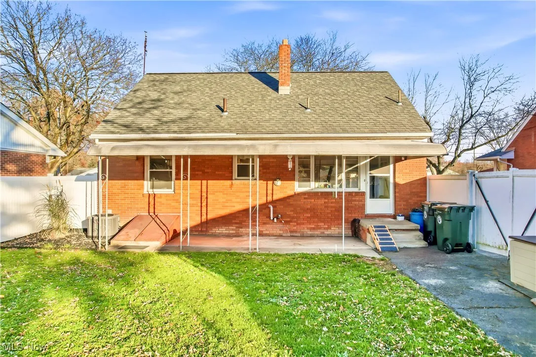 Rear view of house featuring brick siding, a shingled roof, and a chimney