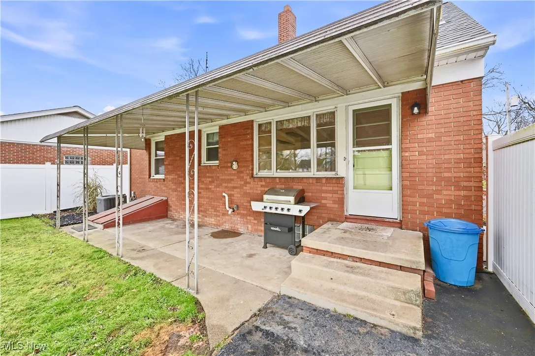Back of house featuring brick siding, a patio, and a chimney