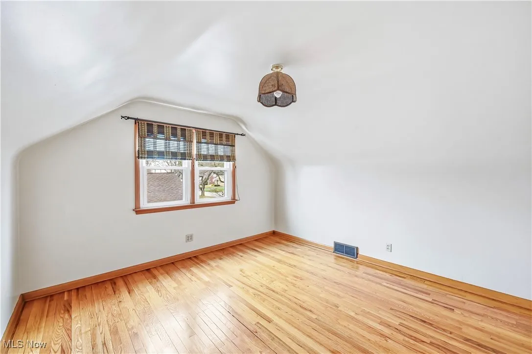 Additional living space with light wood-style flooring and lofted ceiling