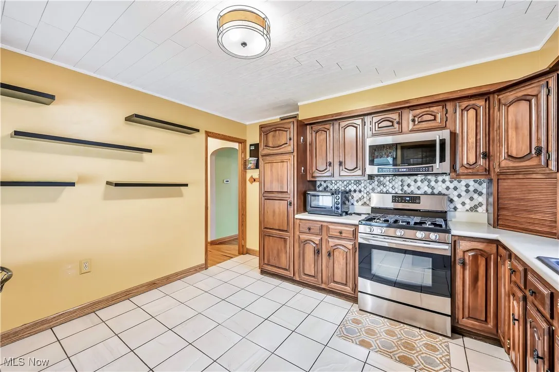 Kitchen with arched walkways, stainless steel appliances, light countertops, and brown cabinets
