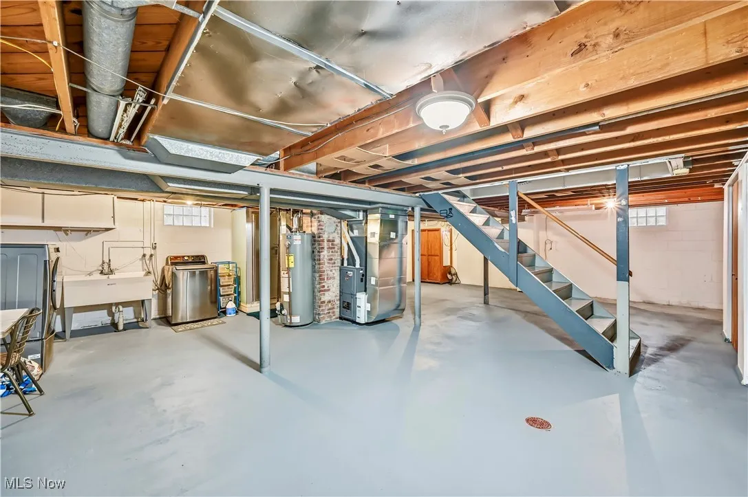 Basement featuring stairway, heating unit, and water heater