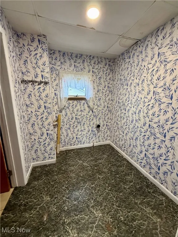 Unfurnished room featuring baseboards and a drop ceiling