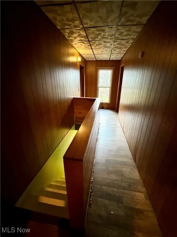 Hall featuring wood walls, an upstairs landing, and a sauna / steam room