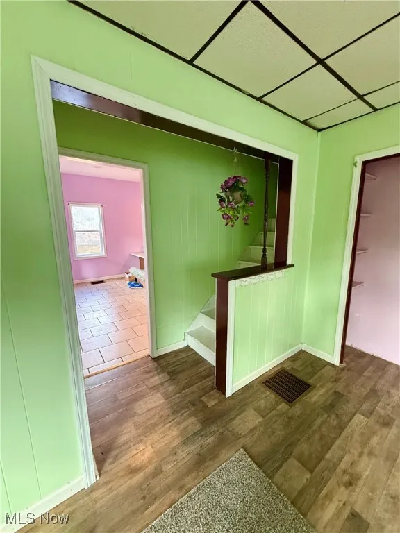 Corridor with wood finished floors and a paneled ceiling