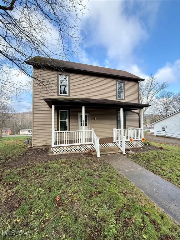 View of front of property with a porch and a front yard