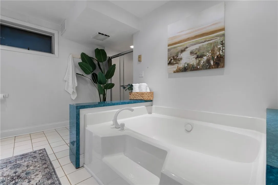 Full bathroom featuring a bath, light tile patterned floors, and a shower stall