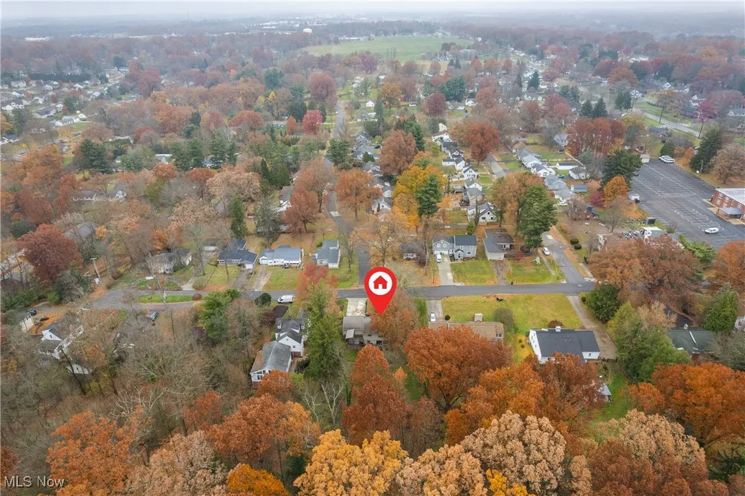 Aerial view of property's location featuring nearby suburban area and a tree filled landscape