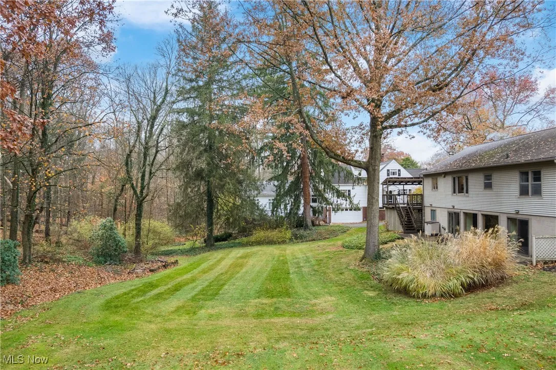 View of grassy yard with stairs and a deck
