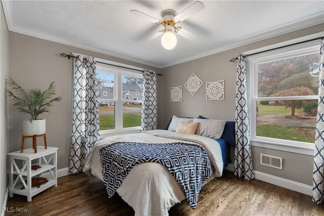 Bedroom featuring ornamental molding, wood finished floors, and a ceiling fan