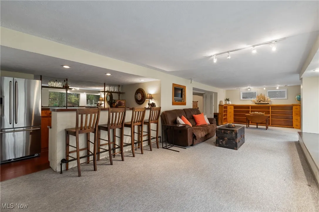 Living room with light colored carpet, bar area, and recessed lighting
