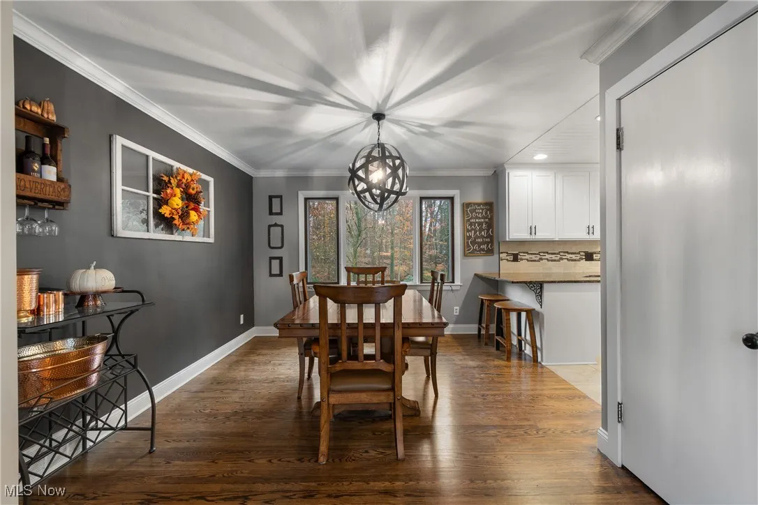 Dining area with ornamental molding, a chandelier, and dark wood finished floors