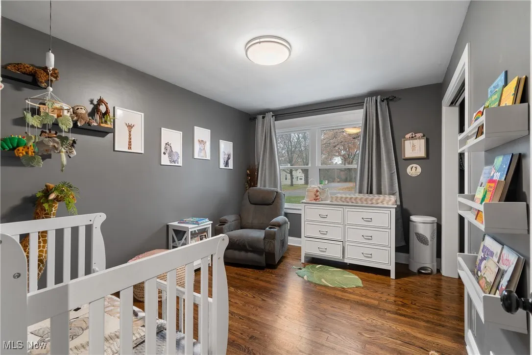 Bedroom featuring a crib and dark wood-style floors