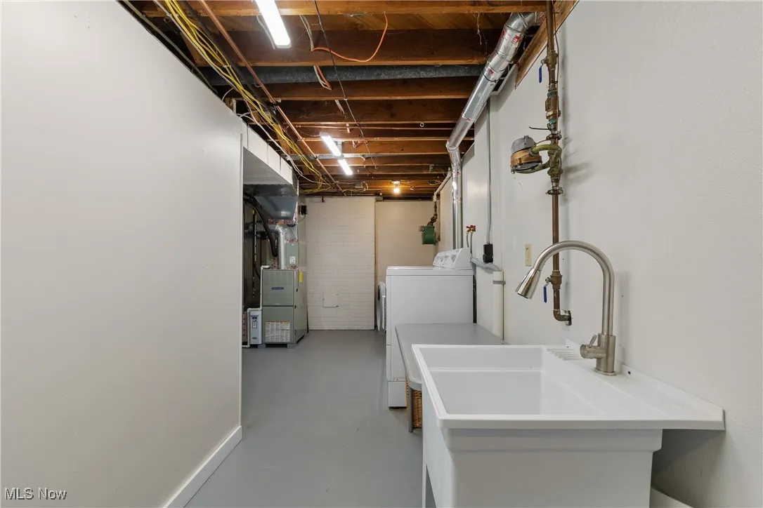 Laundry area with finished concrete flooring, heating unit, and washing machine and clothes dryer