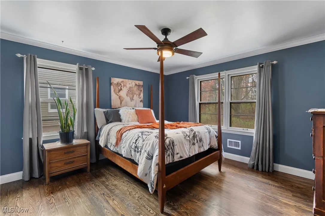 Bedroom with dark wood-style flooring, ceiling fan, and ornamental molding