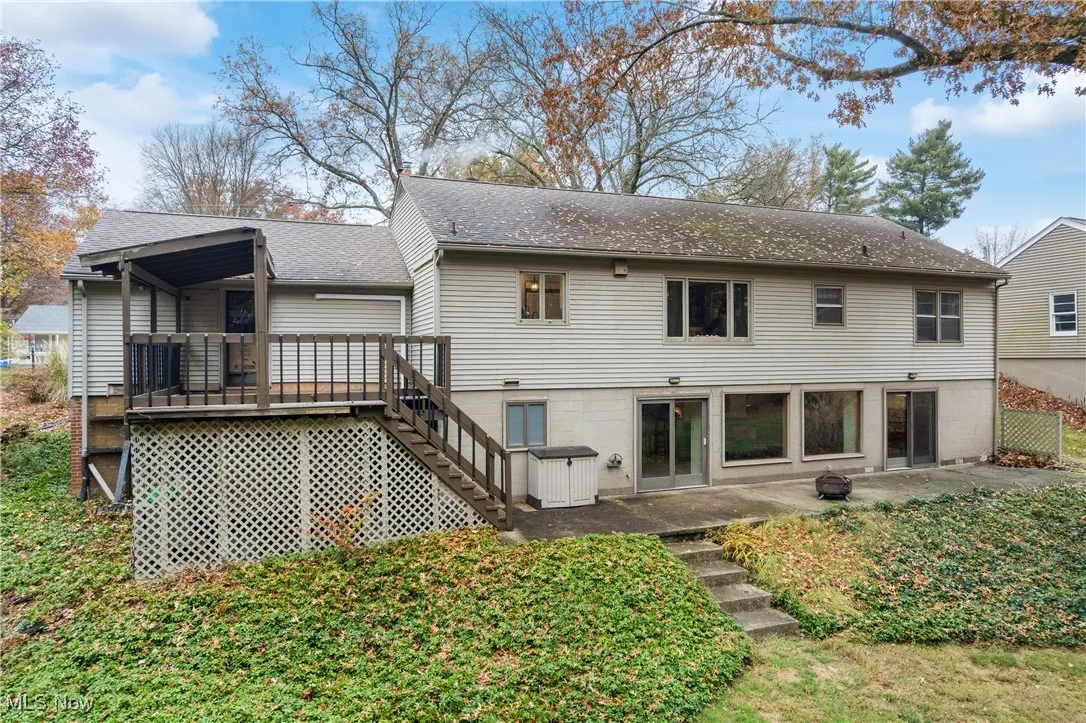 Rear view of property with stairs, a shingled roof, a patio, and a deck