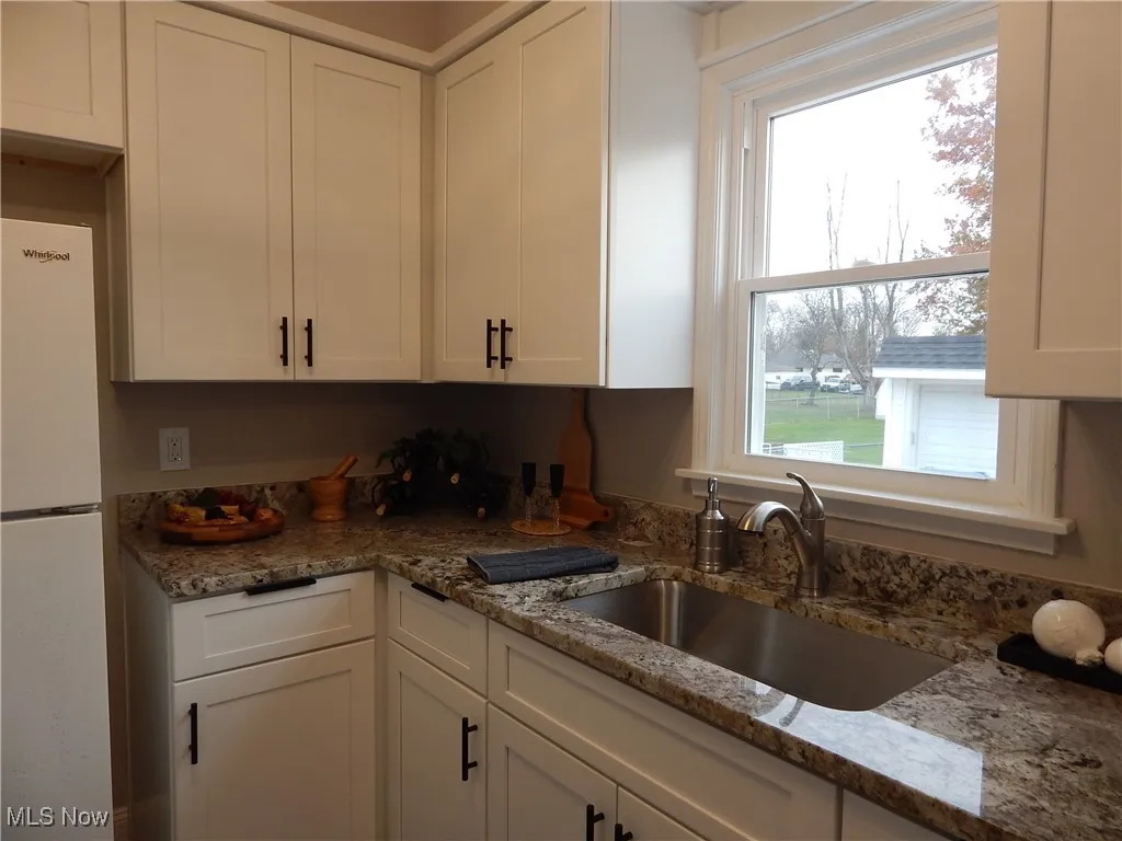 Kitchen featuring white, soft close cabinetry, new window overlooks stainless sink with granite counters.