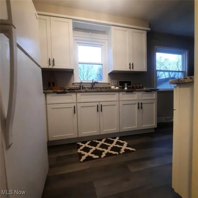 All NEW Kitchen featuring white, soft close cabinets, LVT wood-style floors, and dark stone counters.