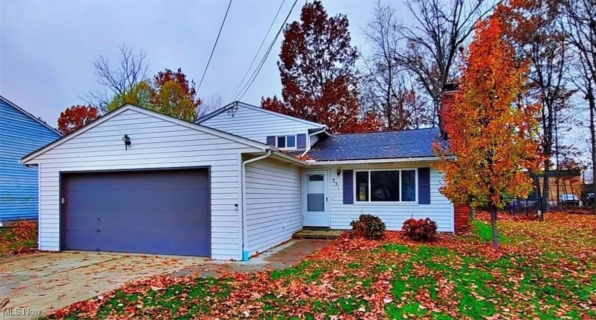 View of front facade with driveway, a garage, and a chimney
