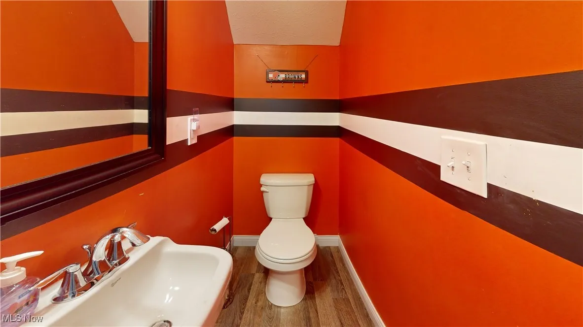 Half bathroom featuring toilet and wood finished floors