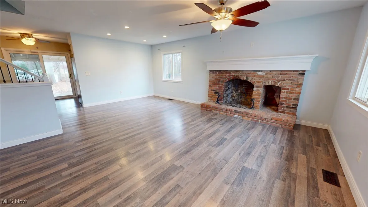 Unfurnished living room featuring ceiling fan, recessed lighting, wood finished floors, a fireplace, and​​‌​​​​‌​​‌‌​‌‌​​​‌‌​‌​‌​‌​​​‌​​ stairs