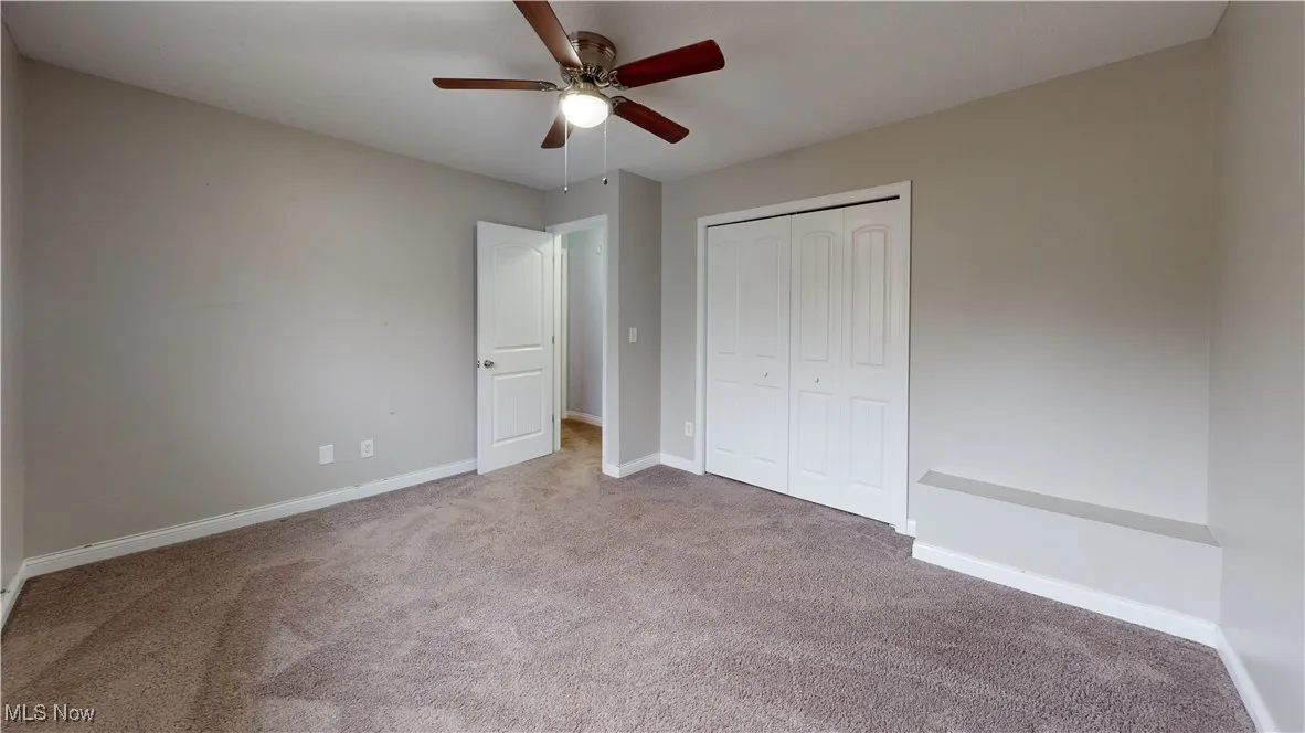 Unfurnished bedroom with carpet floors, a closet, and a ceiling fan