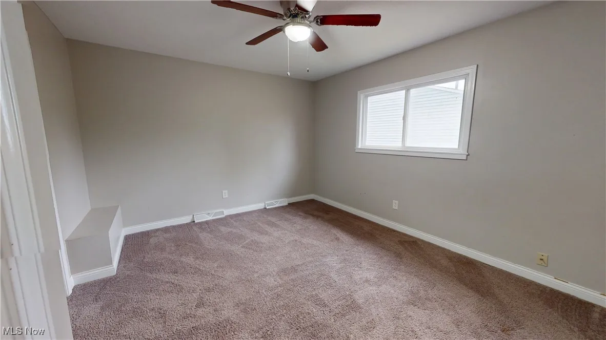 Empty room with light carpet and a ceiling fan