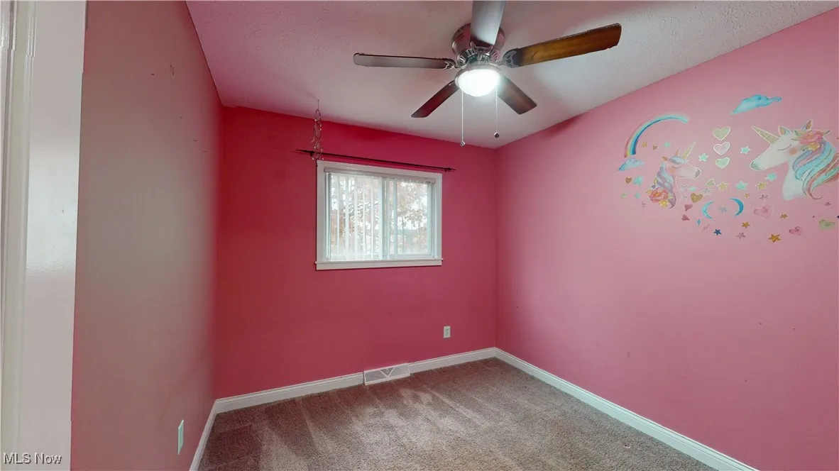 Carpeted empty room with baseboards and a ceiling fan