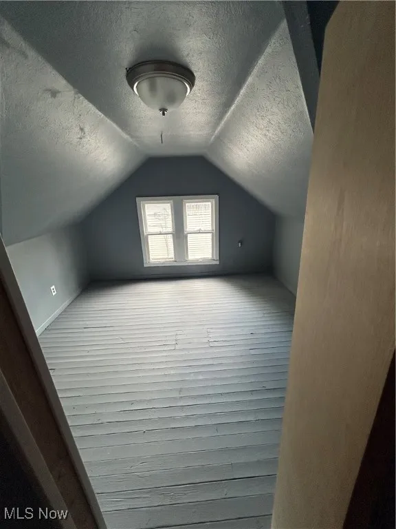 Additional living space with a textured ceiling and lofted ceiling