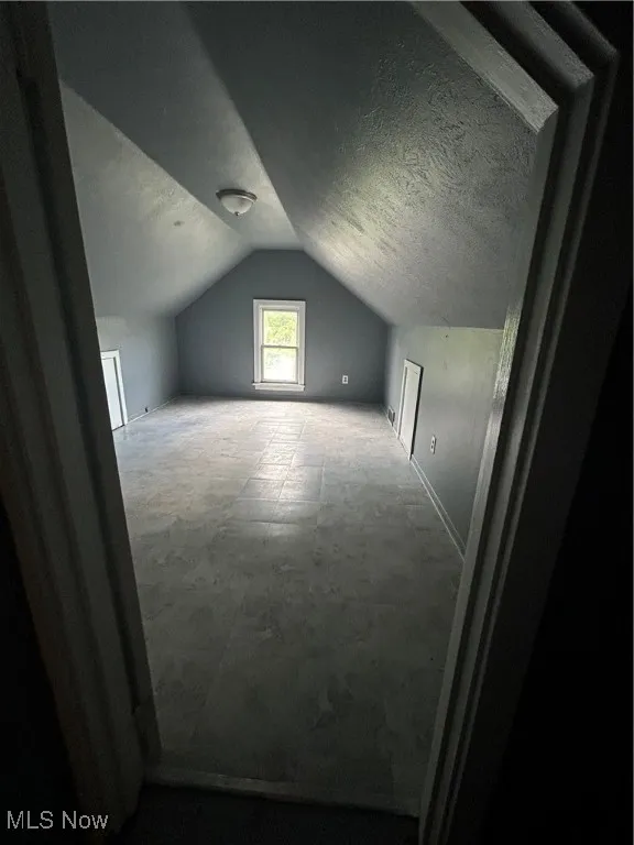 Additional living space with lofted ceiling and baseboards