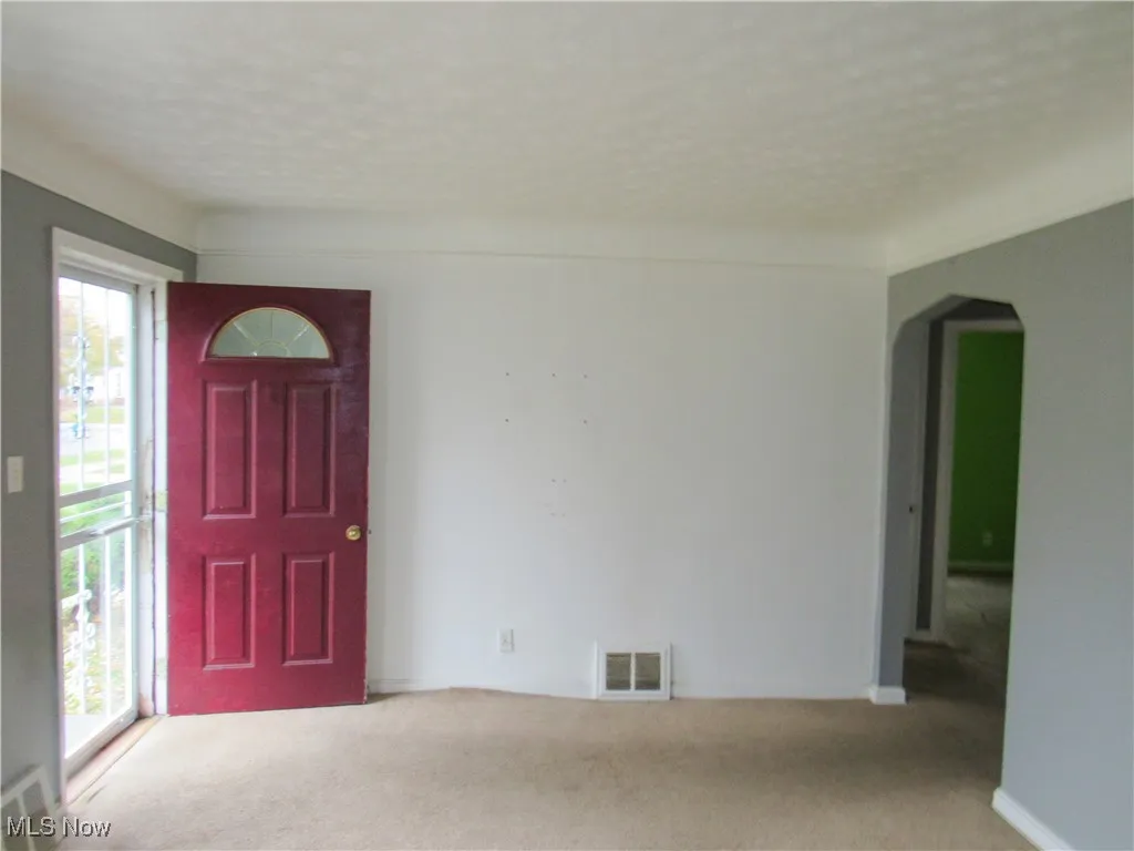 Entrance foyer with arched walkways and carpet flooring