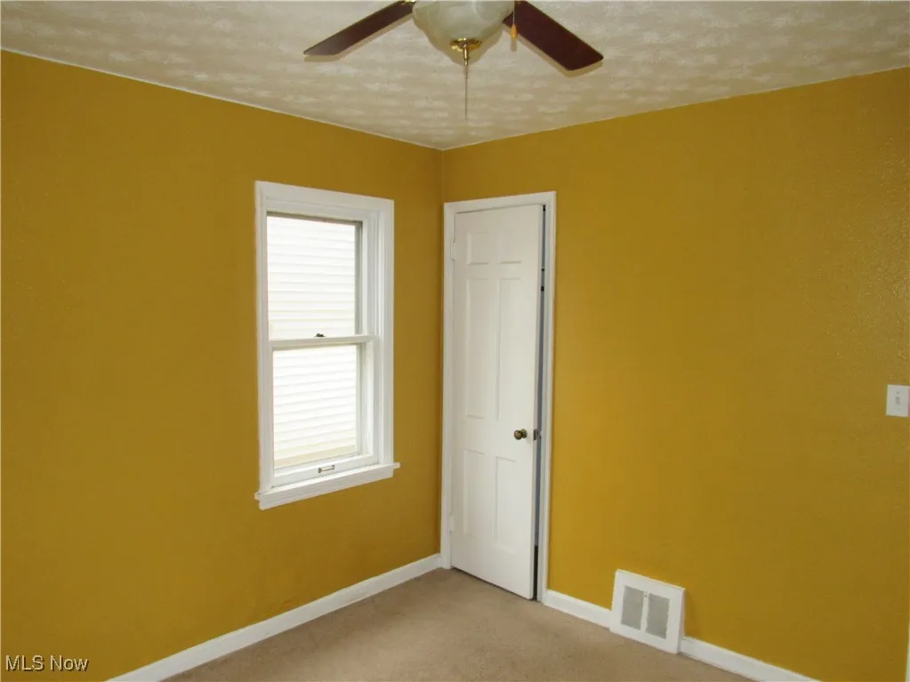 Unfurnished room featuring baseboards and light carpet