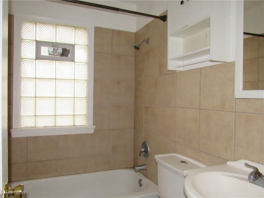 Bathroom featuring  shower combination and tile walls