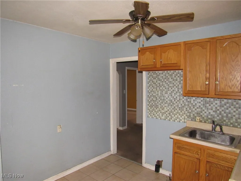 Kitchen with tasteful backsplash, light countertops, brown cabinetry, and light tile patterned floors