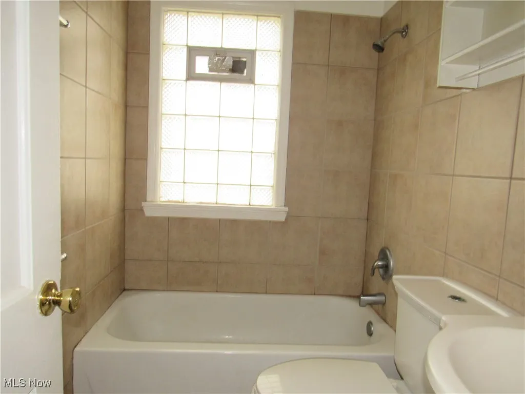 Bathroom featuring tub / shower combination and tile walls