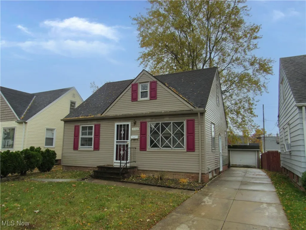 View of front facade with an outbuilding, a front lawn, a garage, a shingled roof, and cooling unit