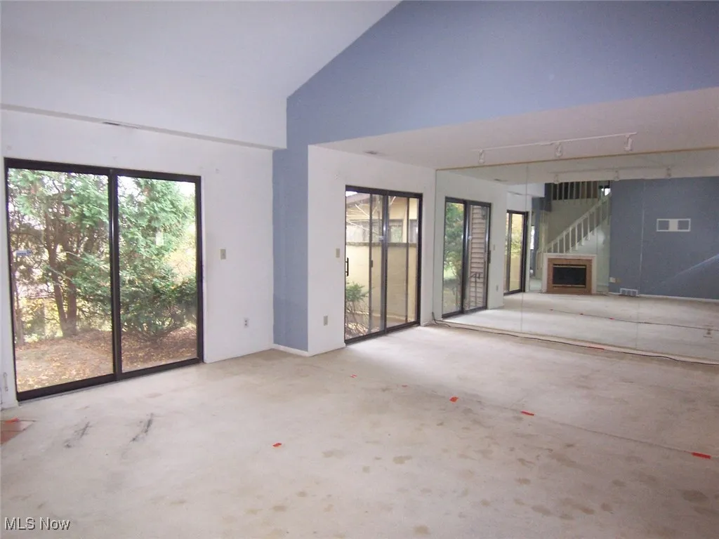 Unfurnished living room featuring high vaulted ceiling