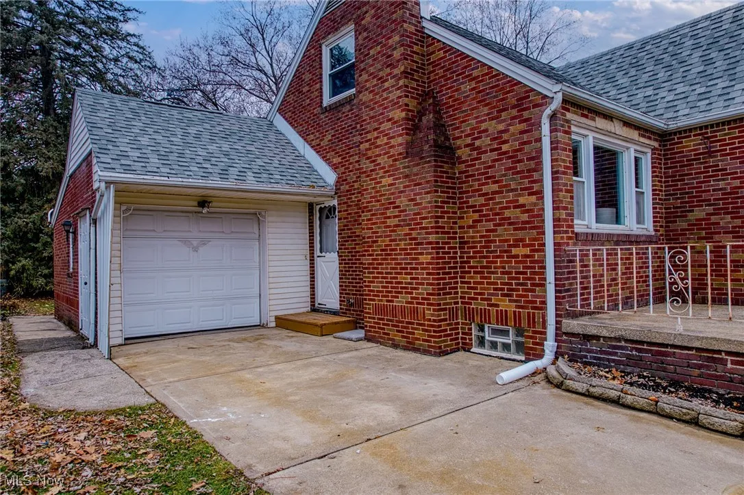 View of home's exterior featuring concrete driveway, an attached garage, roof with shingles, and brick siding
