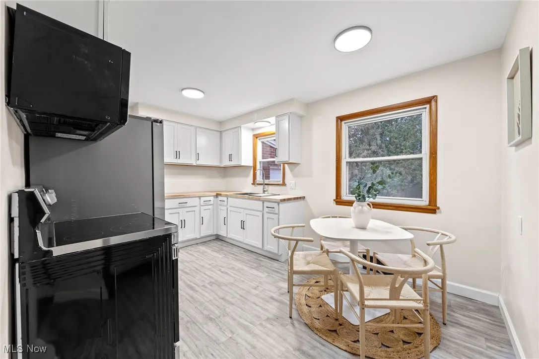 Kitchen featuring black appliances, white cabinets, light countertops, and light wood finished floors