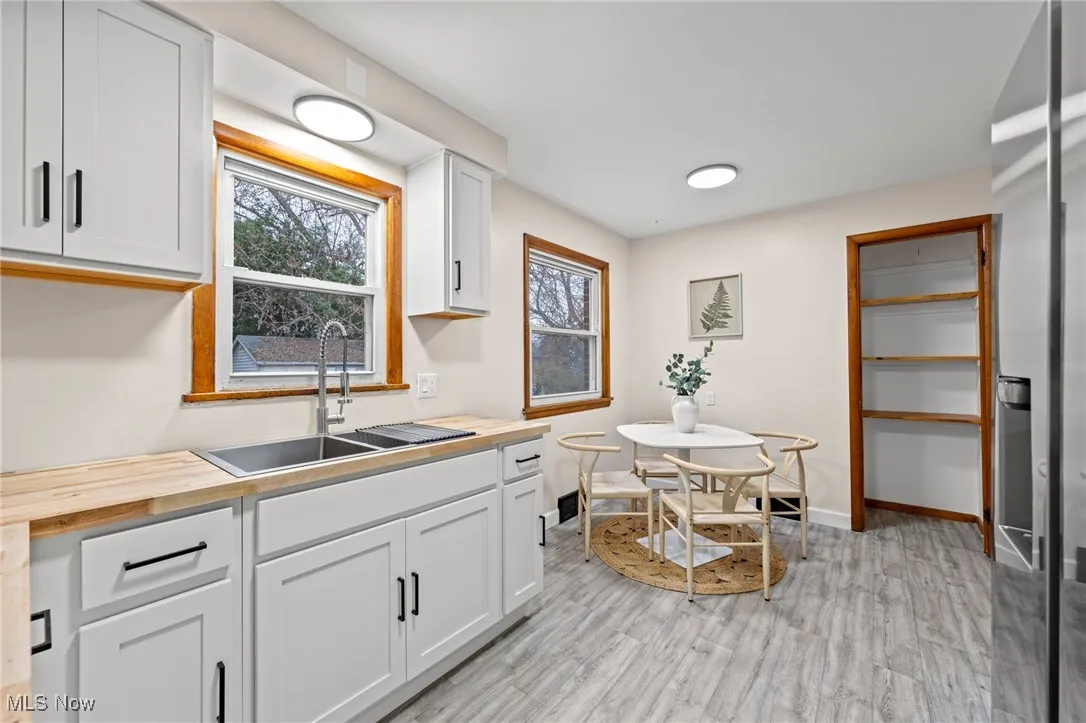 Kitchen featuring butcher block counters, white cabinets, stainless steel fridge, and light wood-style floors