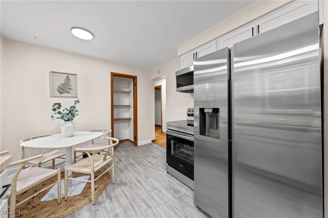 Kitchen with appliances with stainless steel finishes, light wood-style flooring, and white cabinets