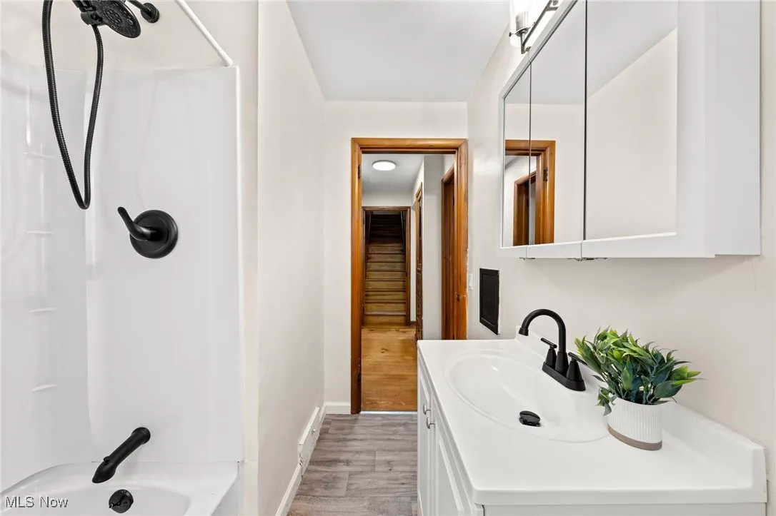 Bathroom featuring shower / tub combination, vanity, and light wood-style floors