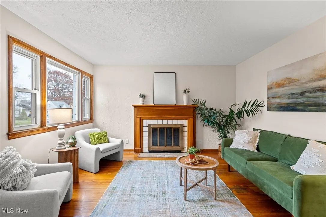 Living area featuring a glass covered fireplace, a textured ceiling, and wood finished floors