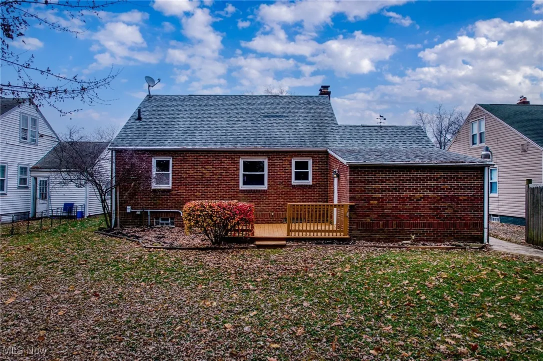 Back of house featuring a wooden deck, brick siding, a shingled roof, and a chimney