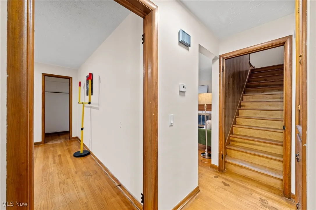 Hall featuring light wood-type flooring, stairs, and a textured ceiling