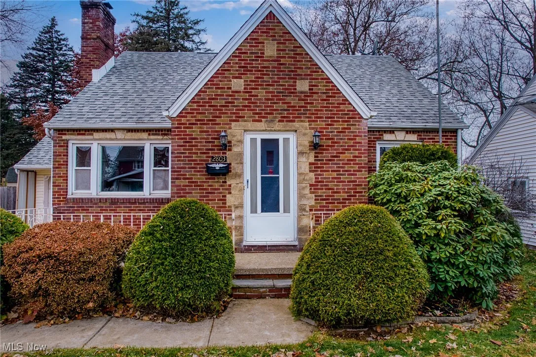 Bungalow-style house with a chimney, roof with shingles, and brick siding