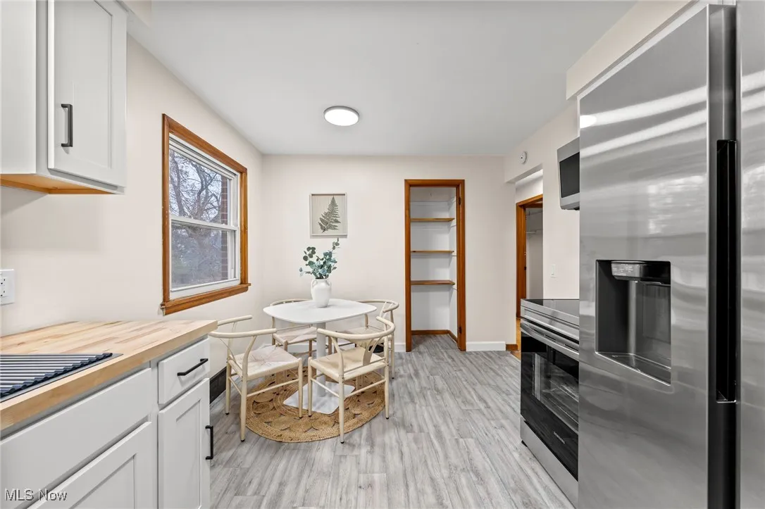 Kitchen with stainless steel appliances, butcher block counters, white cabinetry, and light wood-type flooring