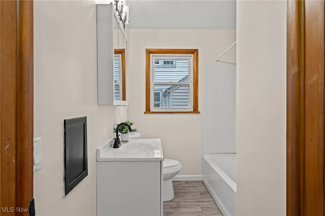 Full bathroom with vanity,  shower combination, and light wood-style flooring